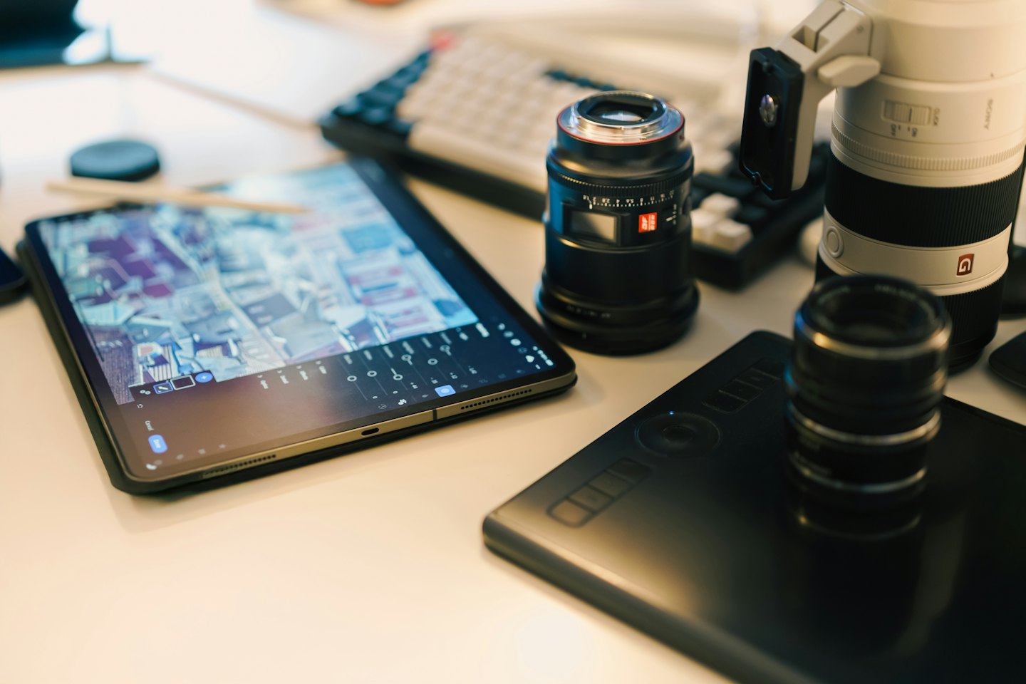 Camera lenses and tablets are arranged on a white desk.
